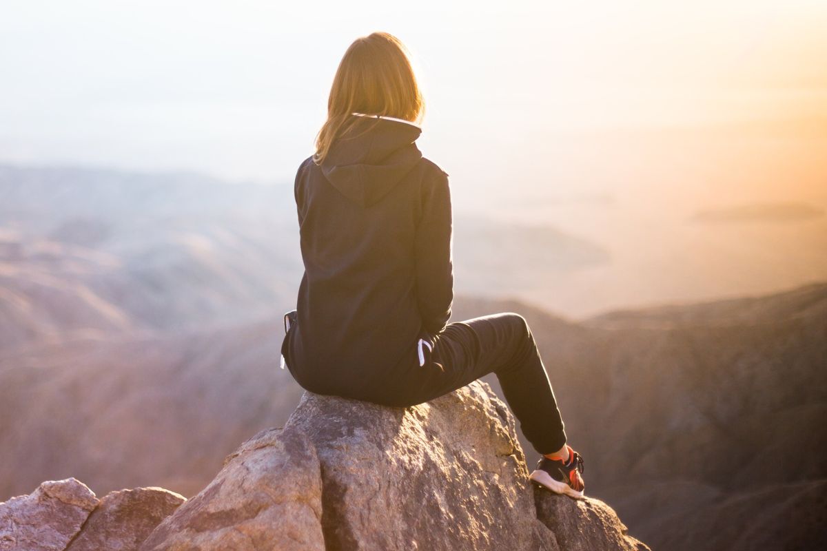 Frau auf Berggipfel, im Sonnenuntergang
