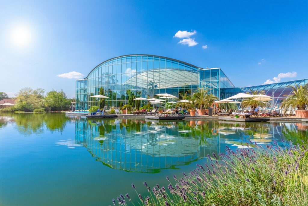 Der idyllische Außenbereich der THERME Bad Wörishofen mit Liegestühlen und Naturbadeteich